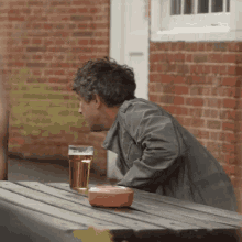 a man sitting at a picnic table with a glass of beer