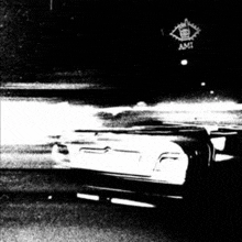 a black and white photo of a car parked in front of a sign that says ami .