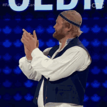 a man applauds in front of a sign that says family feud canada on it
