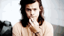 a young man with long hair and a ring on his finger .