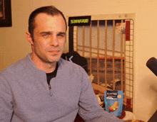 a man sits in front of a shure sign and a bag of planters chips