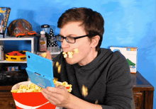 a man is eating popcorn while playing a game on a nintendo ds