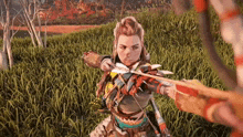 a woman is holding a bow and arrow in a field of grass .