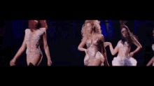 a group of women are dancing on a stage in front of a dark background