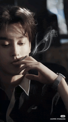 a man is smoking a cigarette in a dark room with a watch on his wrist