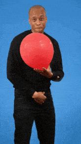 a man in a black sweater holds a red balloon