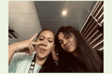 two young women are posing for a picture together and one of them is sticking her tongue out .