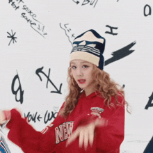 a girl wearing a red new york sweatshirt and a hat