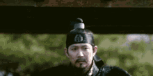 a man with a beard and mustache is wearing a black hat and a black robe .