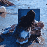 a woman is kneeling next to a trunk with a sticker on it that says ' ambulance ' on it