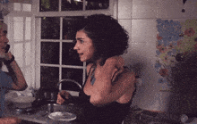 a woman in a black tank top stands in front of a sink