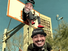 a man wearing a hat that says multivers on it is smiling in front of a basketball hoop