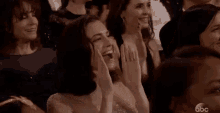 a woman is sitting in a crowd of people applauding .
