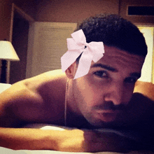 a man with a pink bow on his head laying on a bed