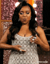 a woman in a silver dress with rings on her fingers is making a face