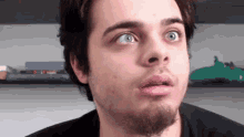 a young man with a beard is making a funny face .