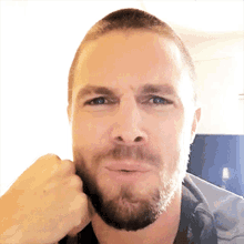 a man with a beard is making a funny face with his fist