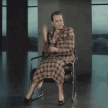 a woman in a plaid dress is dancing in a chair