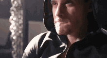 a close up of a man wearing a hooded jacket looking at the camera .
