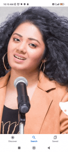 a woman is singing into a microphone on a cell phone screen