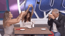 a man and two women are sitting at a table with plates and glasses .