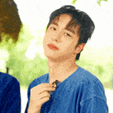 a young man wearing a blue shirt is holding a small object in his hand