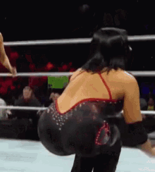 a woman in a red and black dress is standing in a ring .
