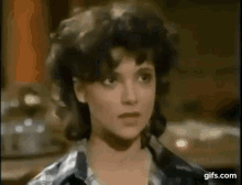 a woman with curly hair is looking at the camera in a close up of her face .