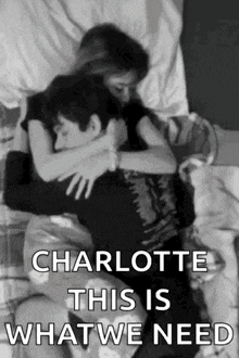 a black and white photo of a man and woman hugging each other on a bed .