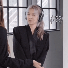 a woman wearing headphones is standing next to another woman with a question mark above her head