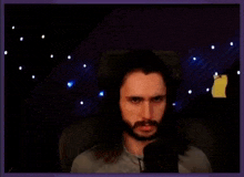 a man with long hair and a beard singing into a microphone .