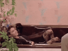 a woman is laying in a bathtub with her feet in the water .