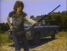 a man is holding a gun in front of a truck .