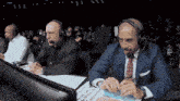 two men wearing headphones are sitting in front of a computer monitor