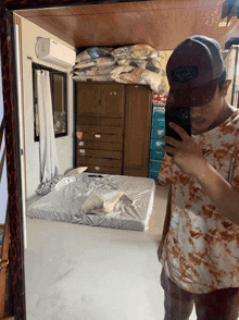 a man taking a picture of himself in a mirror with a hat that says california