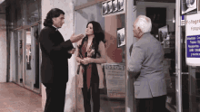a man and a woman are standing in front of a store with a sign that says 070