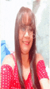 a woman wearing glasses and a red off the shoulder top smiles for the camera