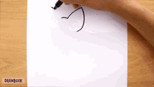 a person is drawing a bird on a piece of paper with drawbook written on the bottom right