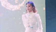 a woman in a white dress is standing on a stage with a microphone in her mouth .