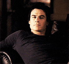 a man in a black shirt is sitting in a chair and looking at the camera