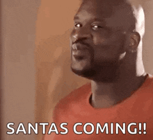 a man in a red shirt is saying santas coming !