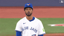 a baseball player for the blue jays is standing on a field