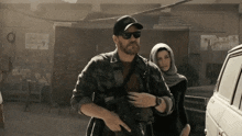 a man with a beard and sunglasses stands next to a woman
