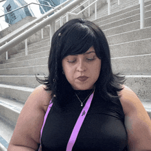 a woman wearing a black tank top and a purple lanyard that says ' vogue ' on it