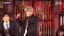 a man in a suit is singing into a microphone in front of a sign that says we are k pop