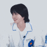 a boy wearing a white jacket with blue flowers on the sleeves