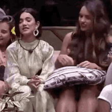 a group of women are sitting on a couch with a pillow .
