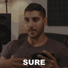 a man holding a cell phone with the word sure written on the screen