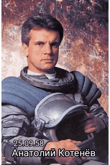 a man in a space suit is holding a helmet with the date 25.09.58 on the bottom