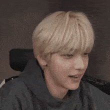 a close up of a person 's face with blonde hair and a black hoodie .